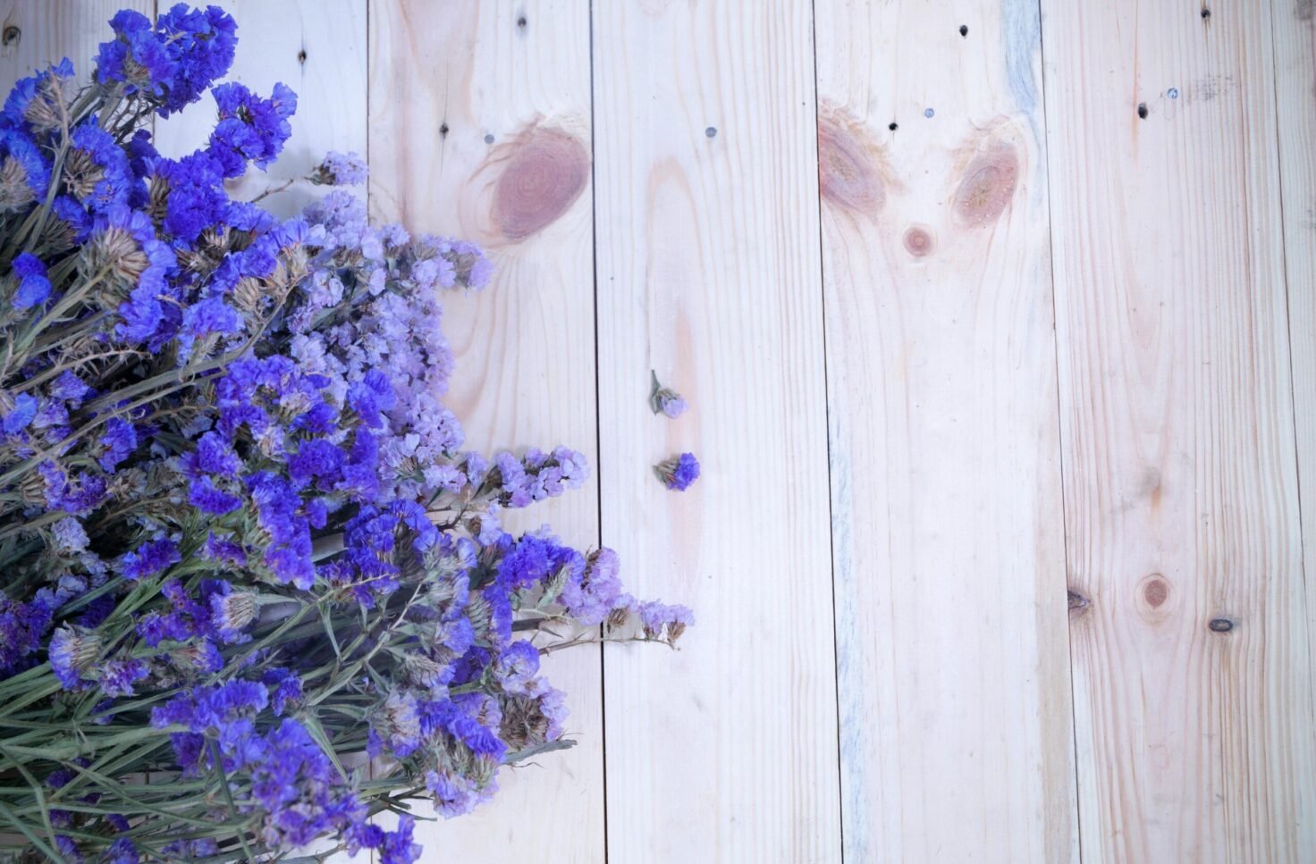 Top view of purple flowers on a light wooden background, offering ample copyspace.